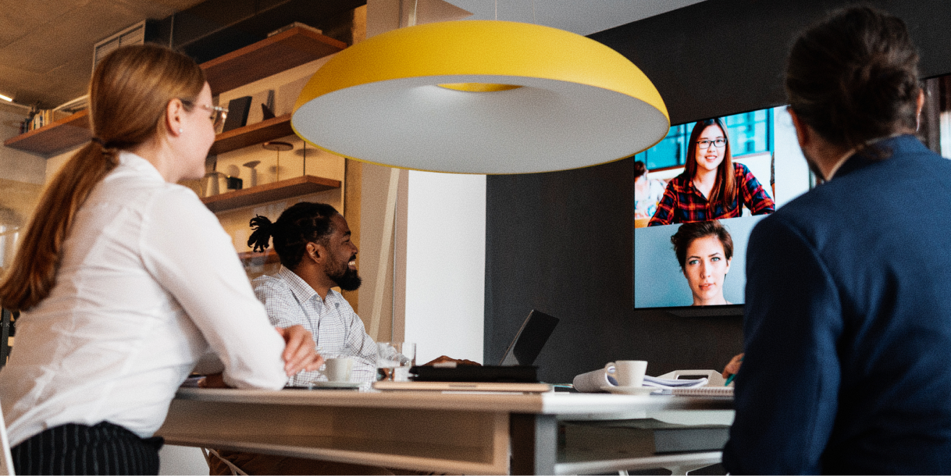 Employees seated around a video conferencing call.