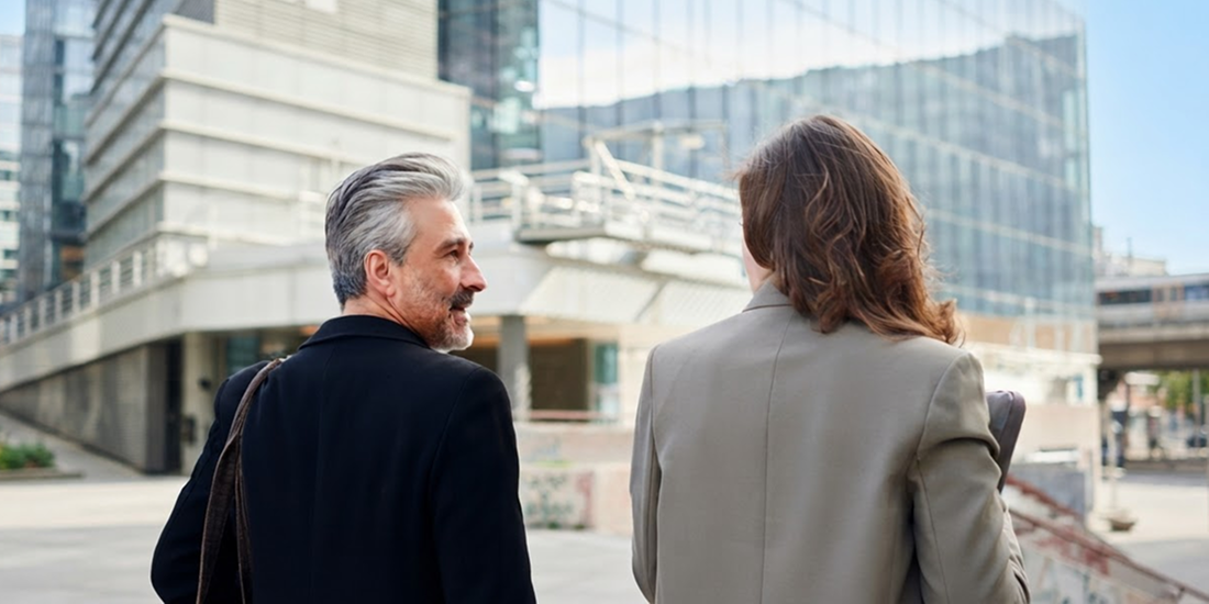 Two people walking in front of an office building.
